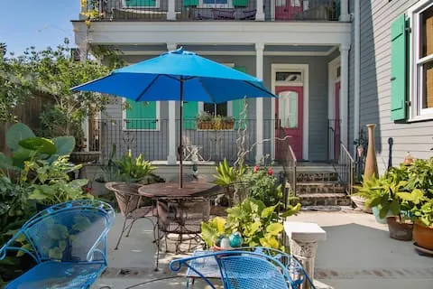 Shared courtyard with garden plants, tables, chairs, and a blue umbrella