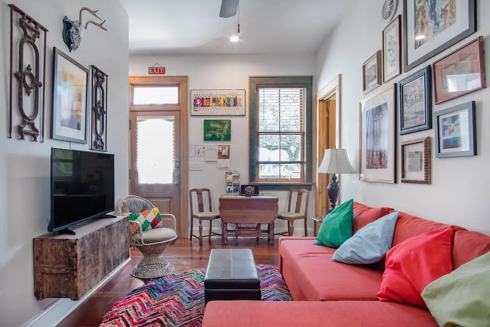In-law suite living room with a coral sofa, framed artwork, and a dining table
